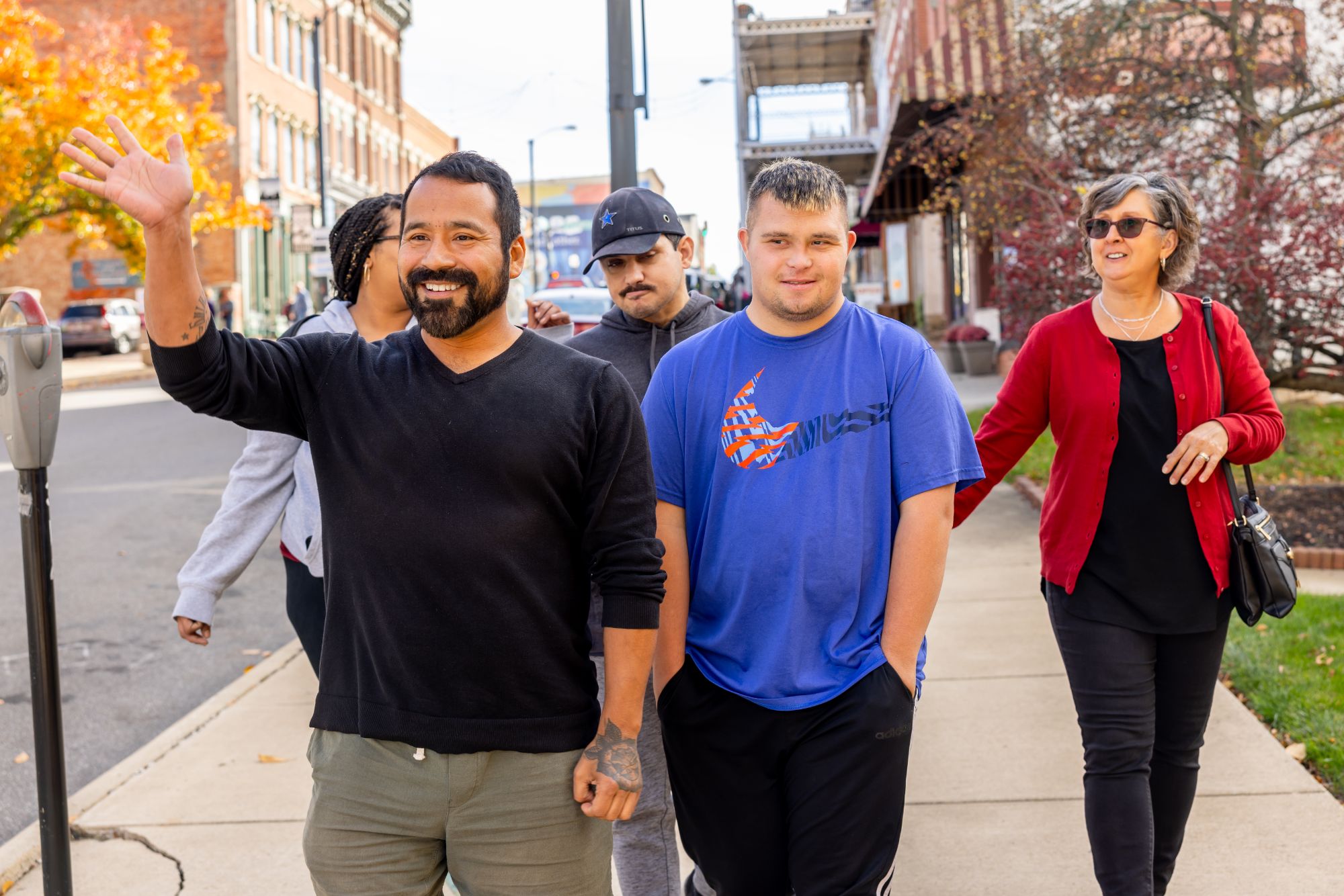 A group walking through Downtown Mansfield. One man is waving to someone out of frame/