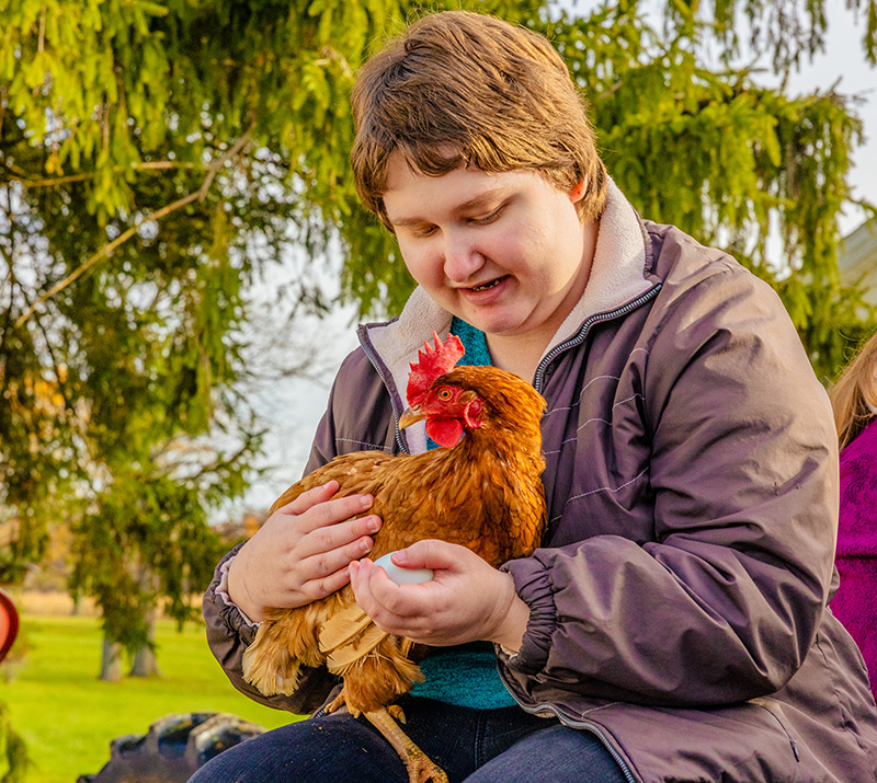 Student holding chicken on the farm